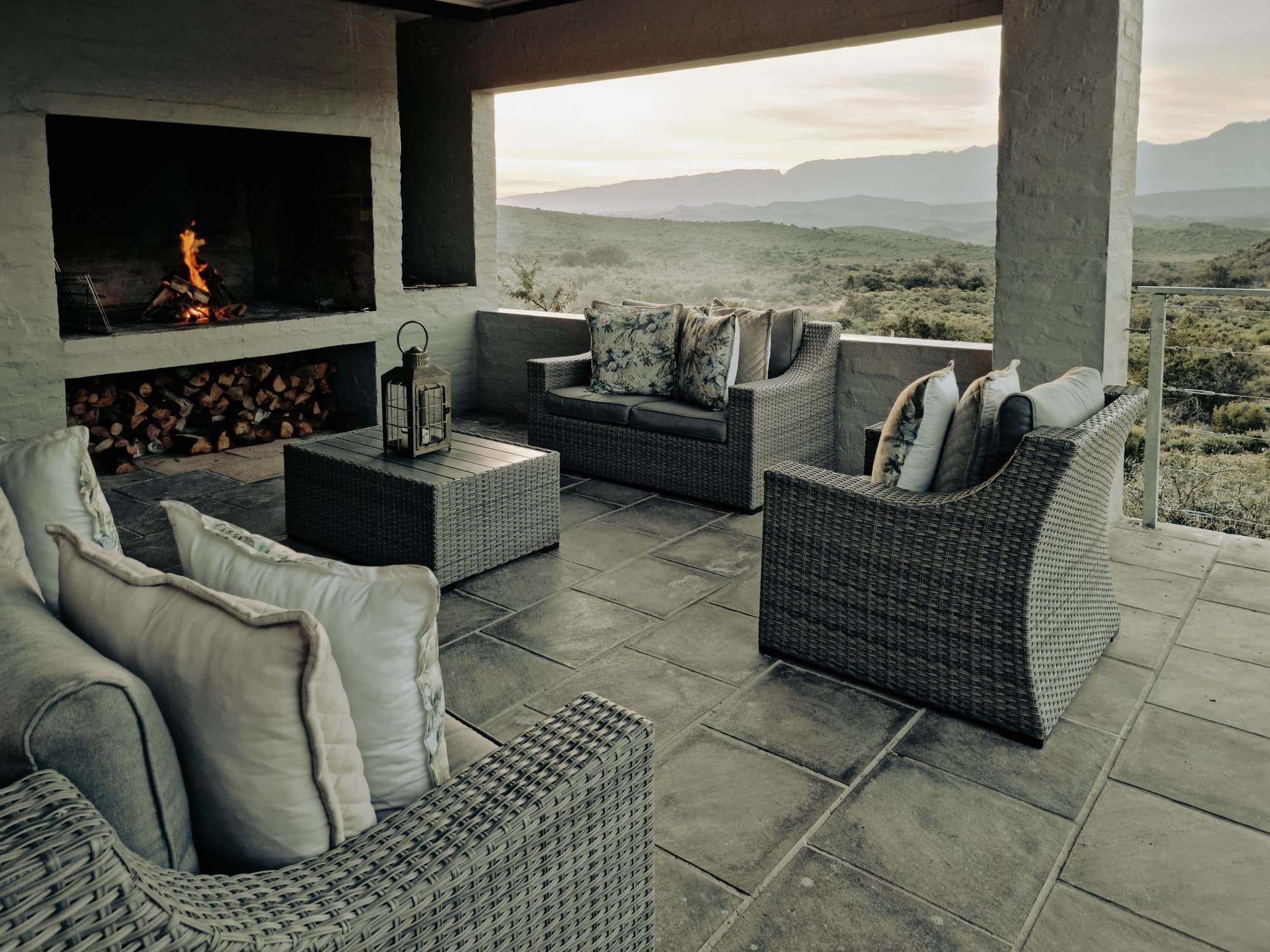 Covered patio with an outdoor fireplace and seating, looking out over hills