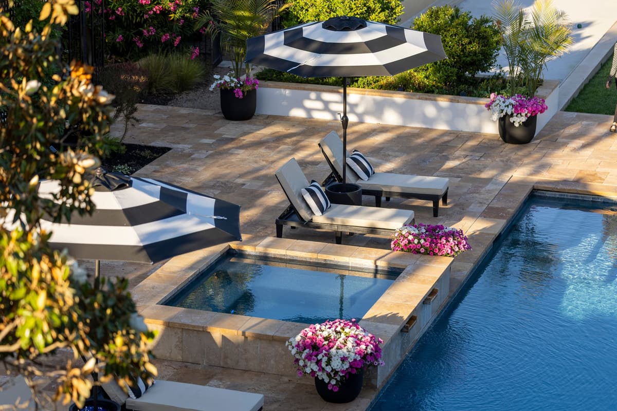 Paver deck around a pool and raised spa, with lounge chairs
