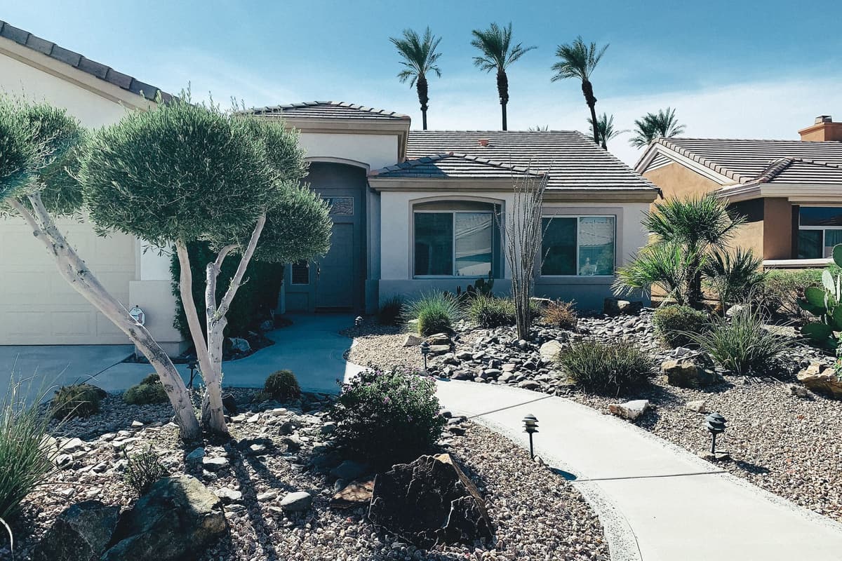 Front yard planted with drought-tolerant shrubs, gravel, and boulders