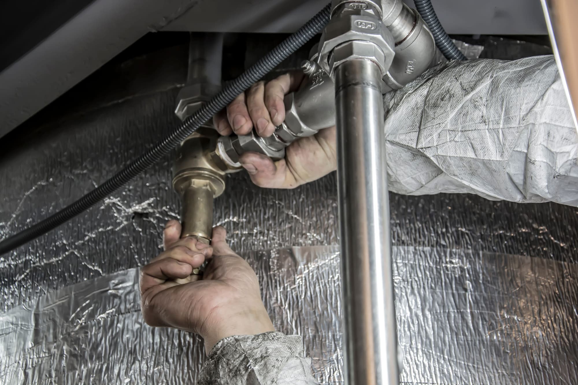 Hands tightening brass and steel pipe fittings